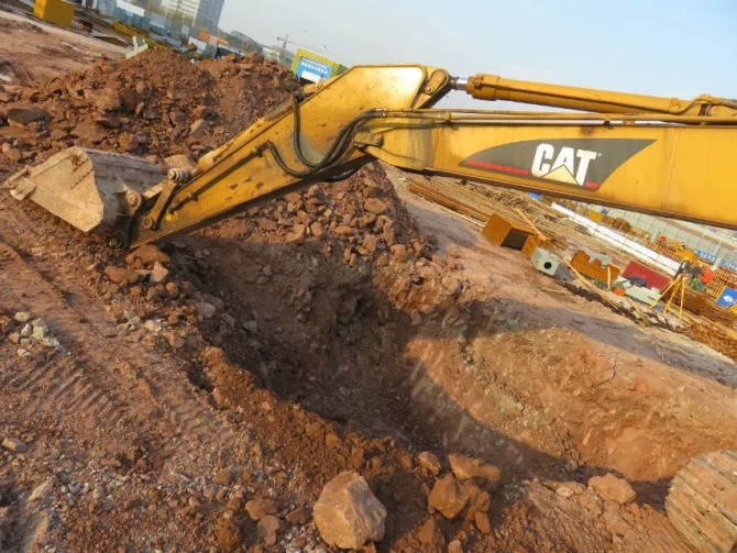 Technician inspecting hydraulic system while checking a used excavator before purchase