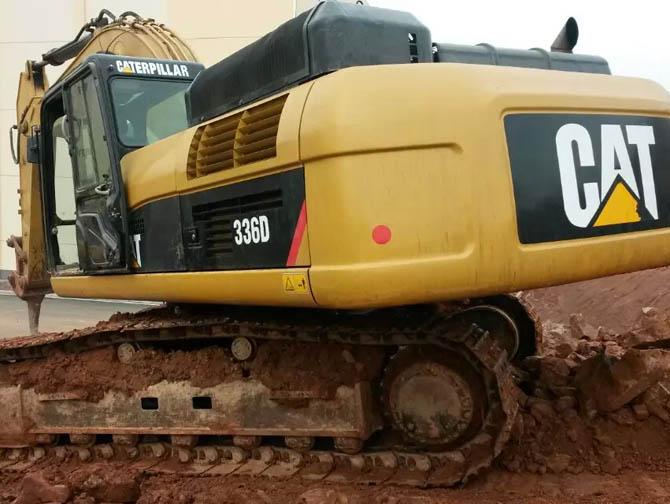 Cat 336 excavator working on construction site with heavy load
